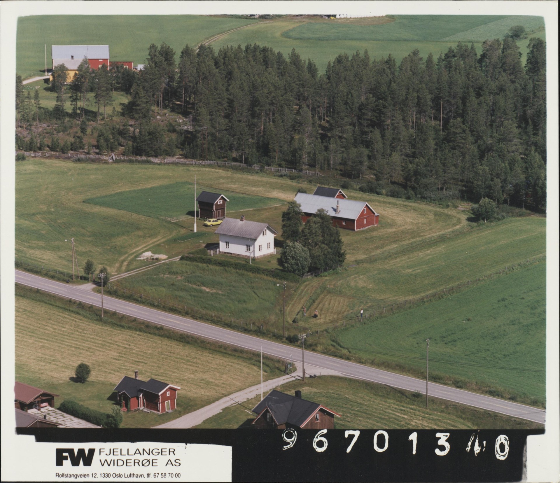 Aerial view of Forest Ranger Farm in 1996, showing the white main house, red barn, and a yellow car by the road.
