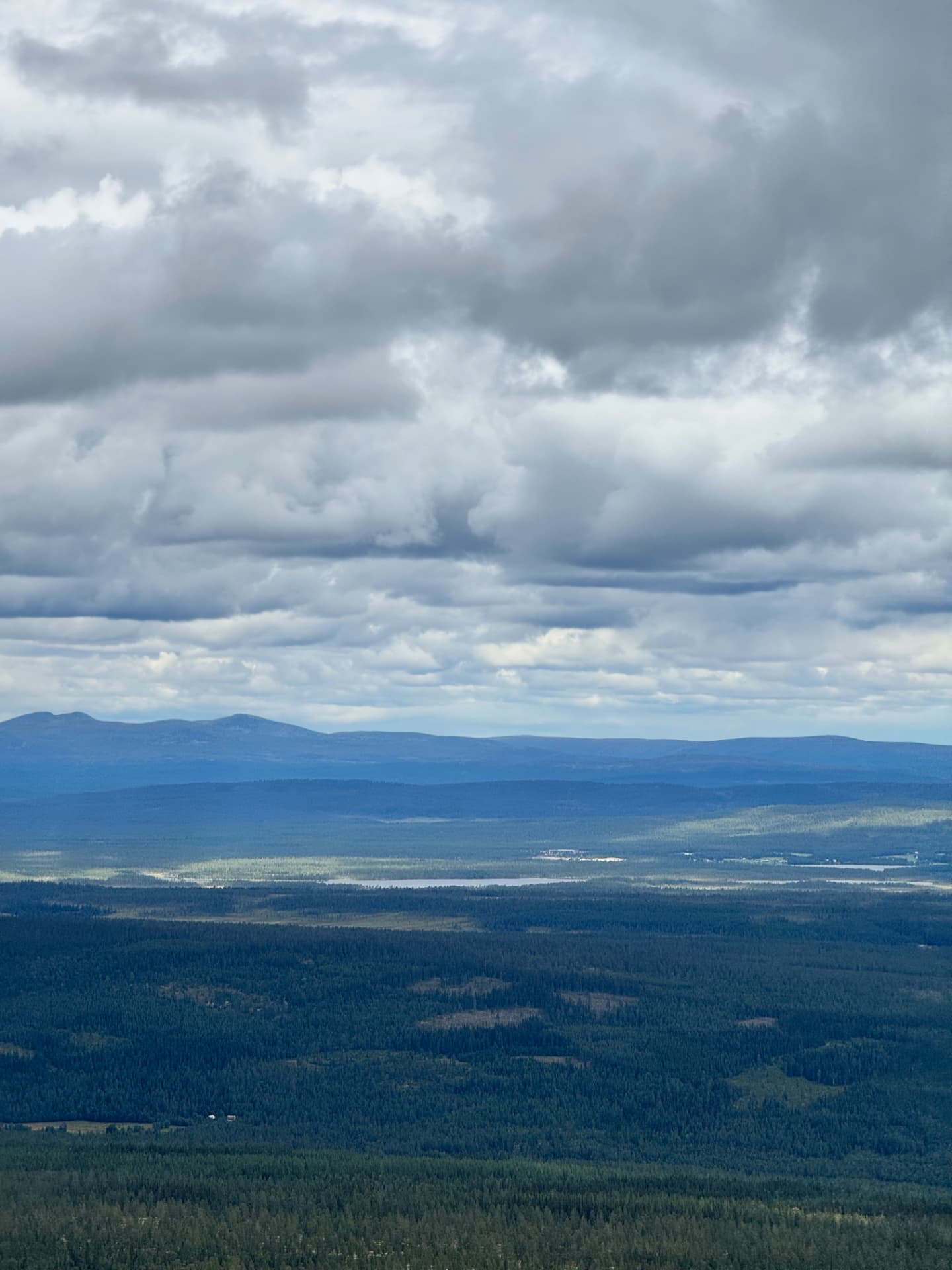 Distant view from the summit down over forest with Drevsjøen lake visible on the right